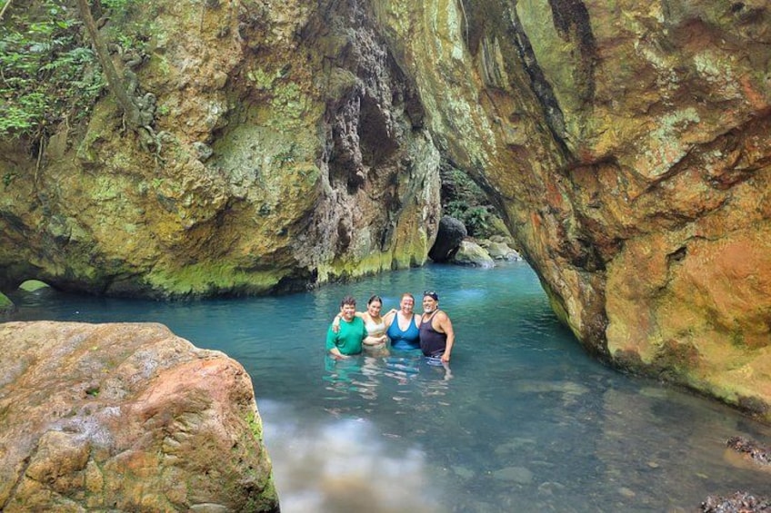 A group of people in a natural water setting surrounded by large rock formations. 4