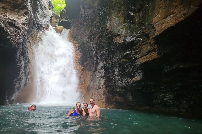 A waterfall in a rocky gorge with people swimming in the water. 5