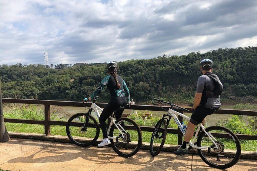 Two cyclists on a bridge overlooking a forested landscape. 4