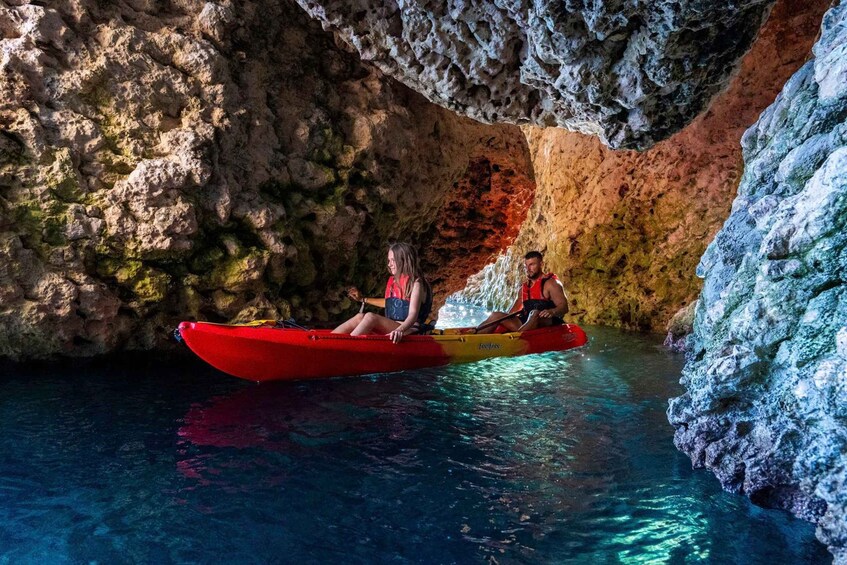Zwei Personen paddeln mit ihren Kajaks in einer Höhle mit Wasser. 3