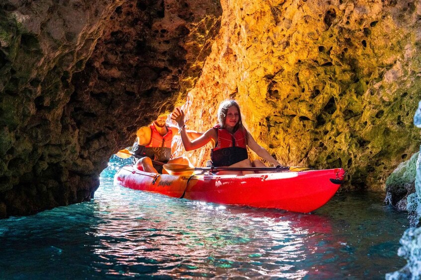 Zwei Personen paddeln in einem roten Kajak durch eine Höhle mit Wasser. 5