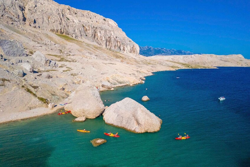 Kajakfahrer auf ruhiger See mit felsigen Klippen und klarem, blauem Wasser. 4