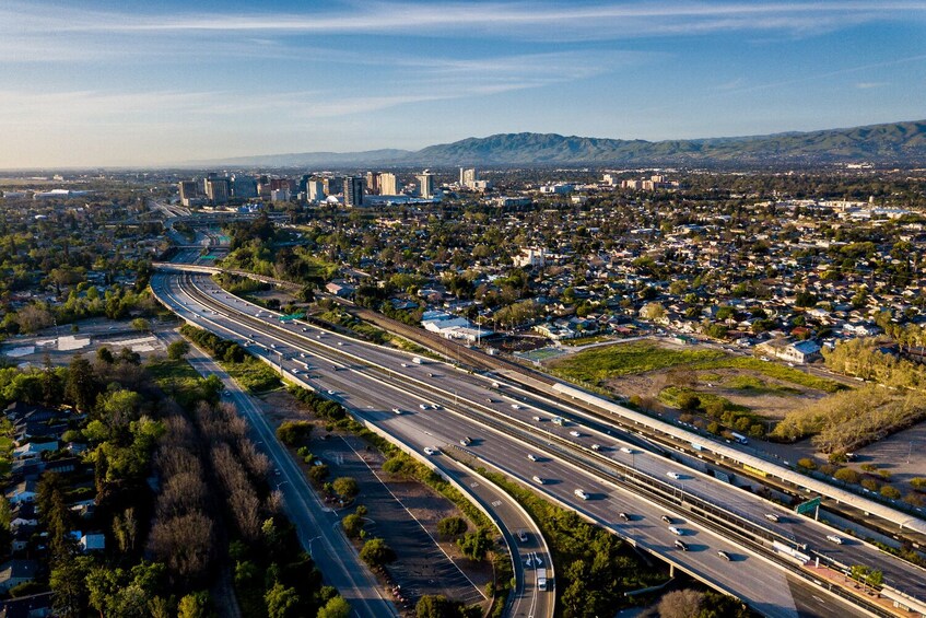 A multi-lane highway with moderate traffic, surrounded by residential areas and distant mountains. 5