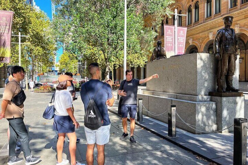 Una estatua sobre un pedestal, personas caminando y un edificio al fondo. 3