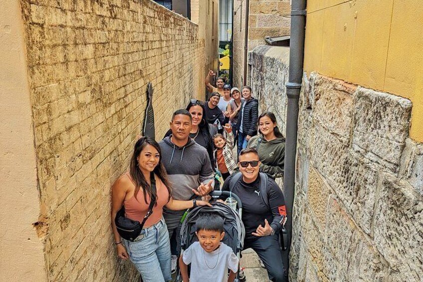 Un grupo de personas en un callejón estrecho con paredes de piedra y un edificio amarillo. 2