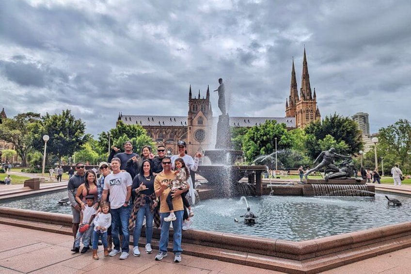 A group of people posing in front of a fountain with a church in the background. 5