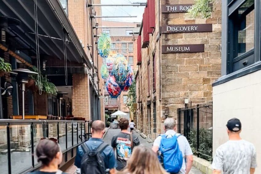 A narrow alley with brick buildings, a mural, and signs for 'The Rock Discovery Museum.' 4