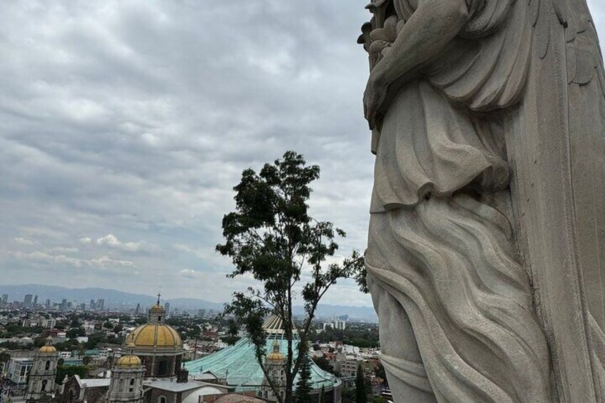 A statue, a tree, and a cityscape with a prominent dome. 4