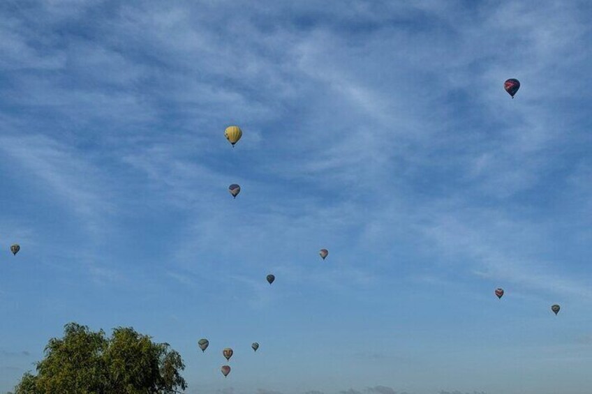 A clear blue sky with multiple hot air balloons in various colors. 2