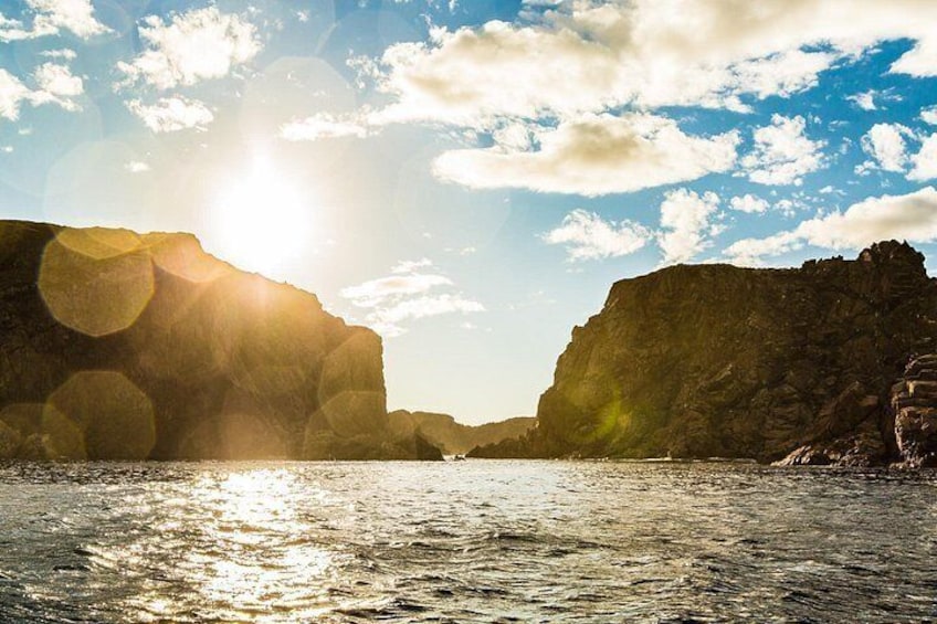 Un paysage côtier avec des falaises et une étendue d’eau reflétant la lumière du soleil. 2