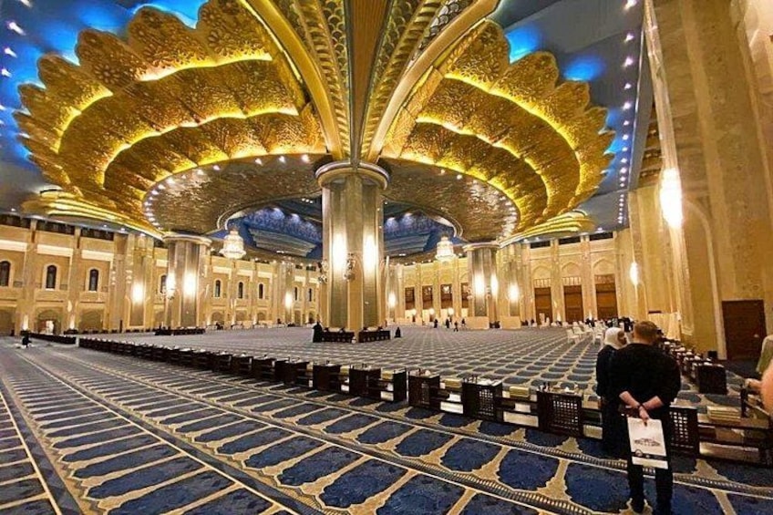 A grand hall with a large stage, ornate ceiling, and rows of seating. 5