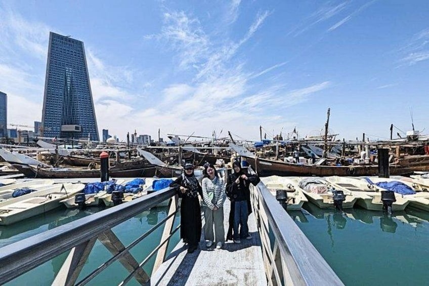 A marina with boats docked, a large modern building in the background, and a clear sky. 3
