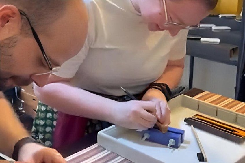 Two people working with a blue box and tools on a table. 1