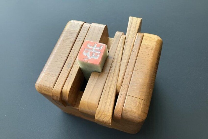A wooden puzzle with a red block on top. 3