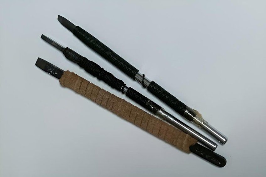 Three tools with handles, one with a cork grip and the others with black grips. 2
