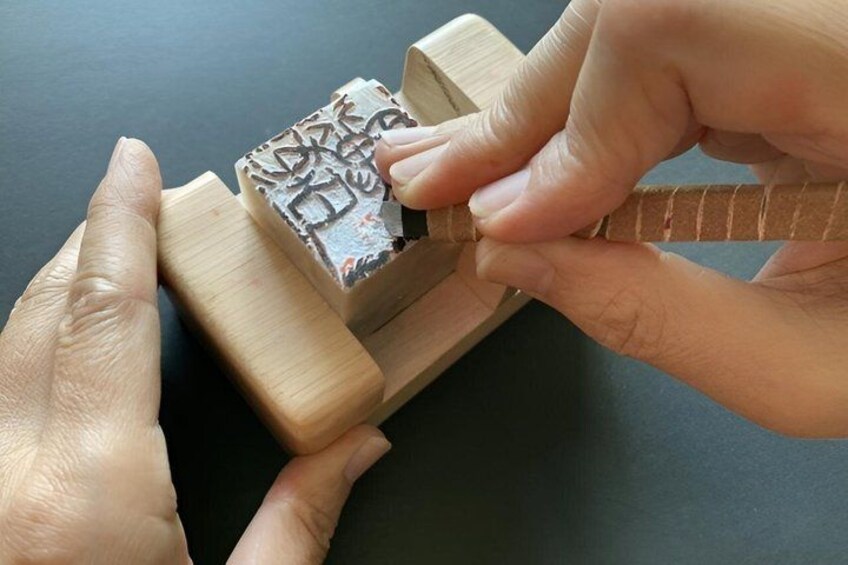 Hands using a wooden stamp to press an object. 5