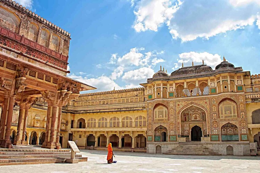 A historic building with intricate architecture, a courtyard, and a person walking. 2