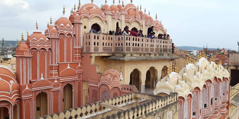 A historic building with ornate architecture, including domes and arches, and a balcony with people. 5