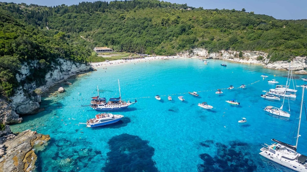 A coastal area with clear turquoise waters, boats, and a beach with people. 5