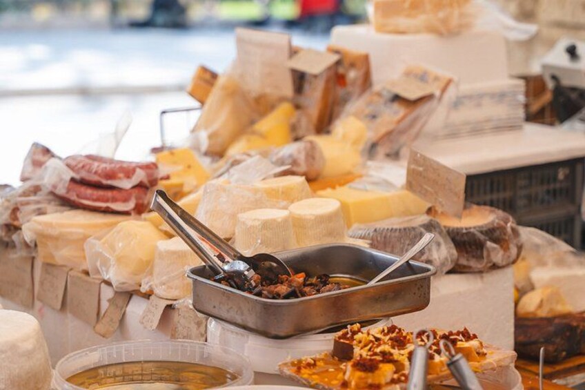 A variety of cheeses and meats displayed in a market setting. 3