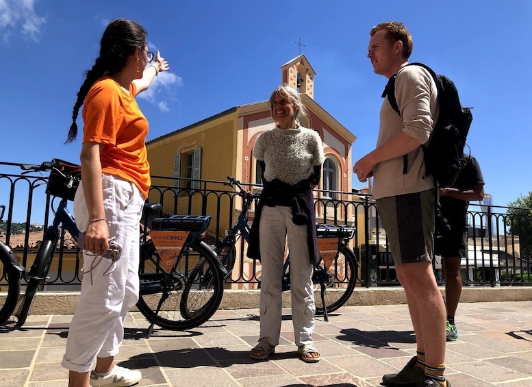 Three people standing outdoors with bicycles and a church in the background. 4