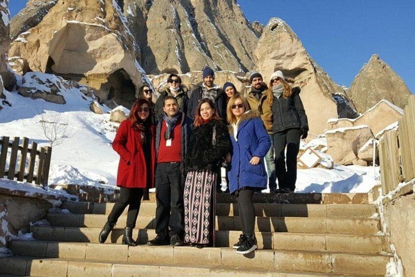 A group of people standing on stone steps with a mountainous landscape in the background. 1
