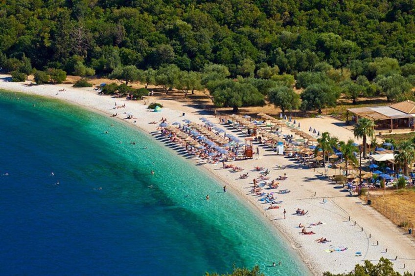 A beach with clear turquoise water, a sandy shore, and a line of umbrellas and sunbeds. 2
