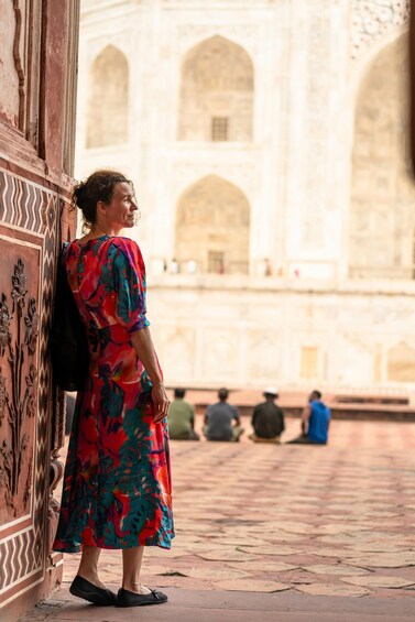 A person in a colorful dress standing in a courtyard with arches and a patterned wall. 2