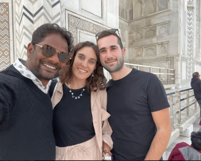 Three people posing in front of a marble building with intricate patterns. 4