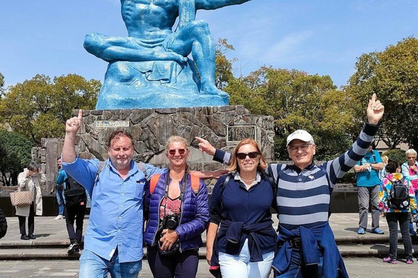 A group of people posing in front of a large blue statue. 1