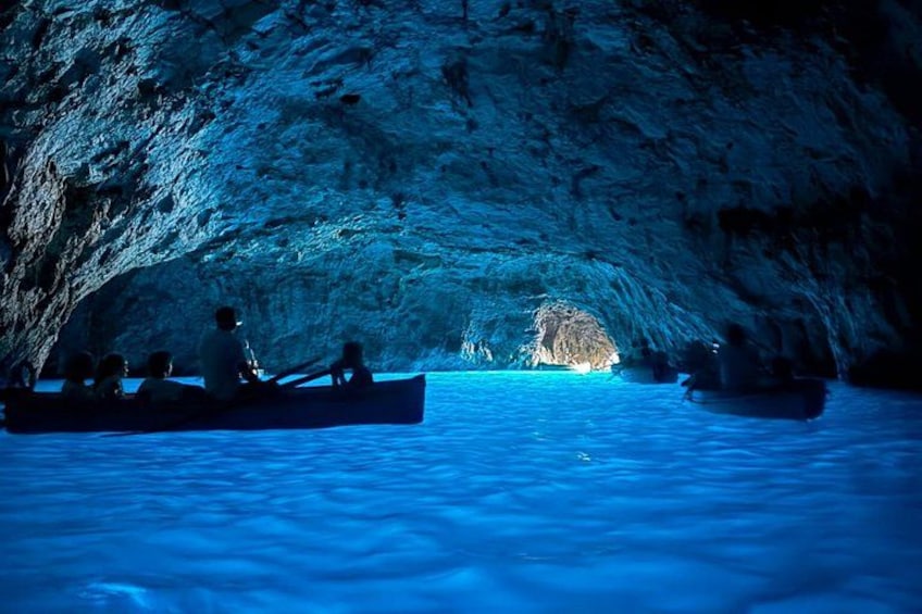 People in canoes inside a cave with water. 1