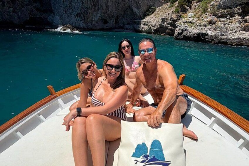 A boat with people on it, rocky cliffs, and clear blue water. 3