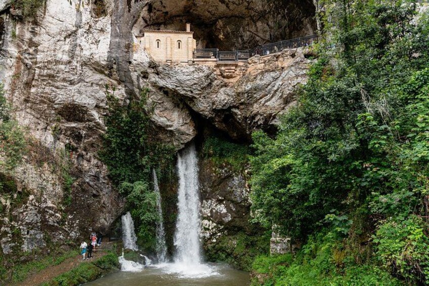 A waterfall cascading into a river, surrounded by lush greenery and a stone building on a cliff. 3