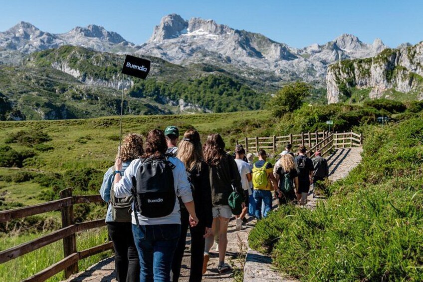 A group of hikers on a trail with a sign reading 'Buondia' and mountains in the background. 5