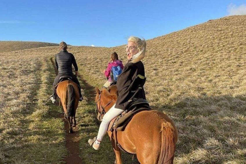 Tres personas montando a caballo por un camino empedrado en una zona montañosa. 5