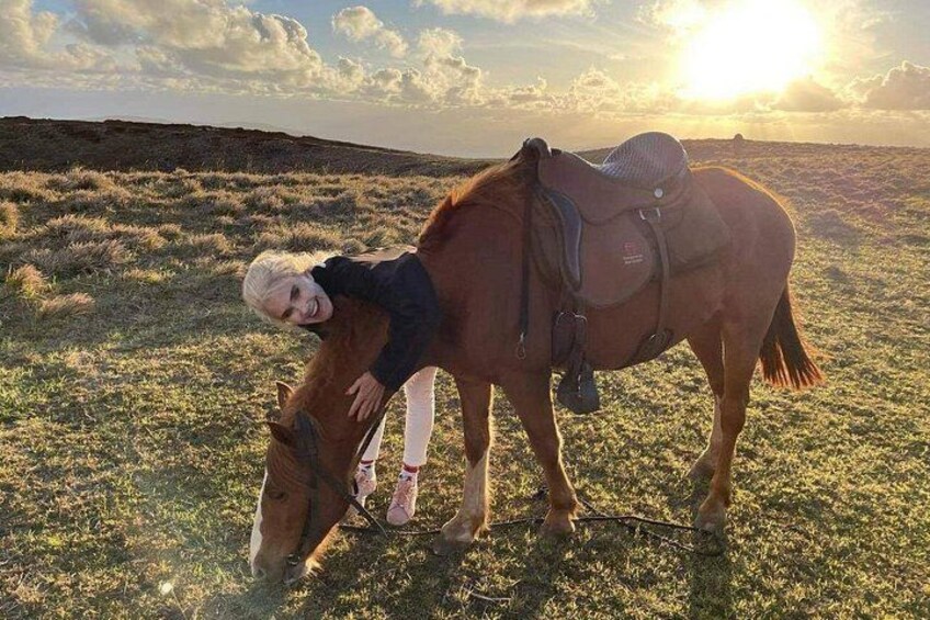 Una persona con un caballo en un campo de hierba, con una silla de montar, bajo un cielo despejado. 3