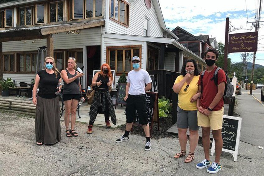 En grupp människor står framför en byggnad med en skylt som visar texten ”Bar Harbor Wine Company”. 3