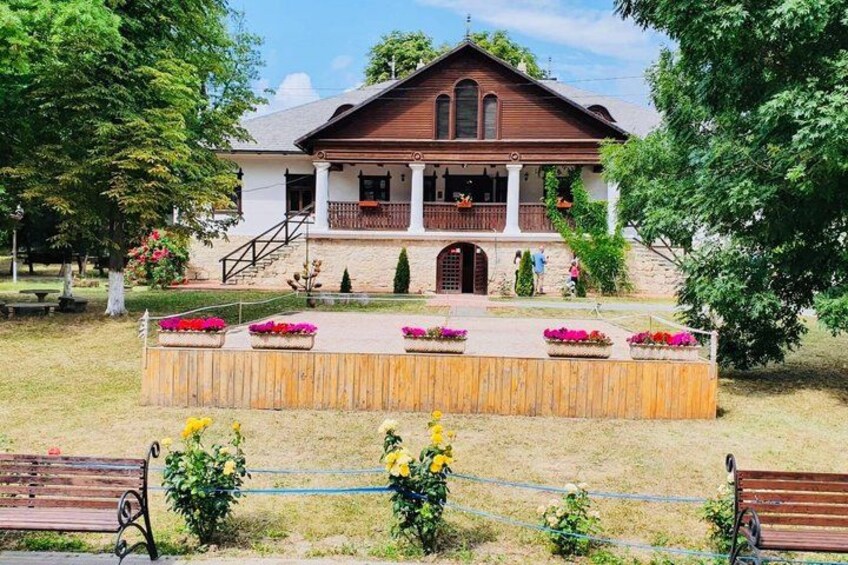 A wooden stage with flower beds, a bench, and a building with a porch. 4