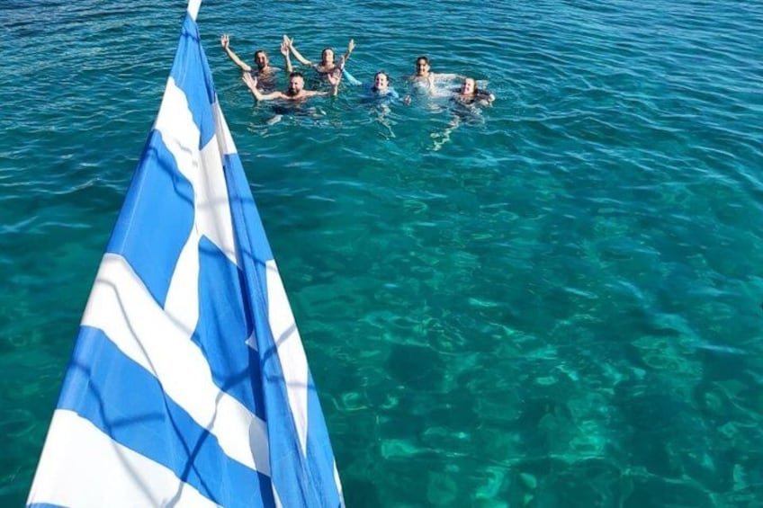 A group of people swimming in clear blue water with a flag in the foreground. 4