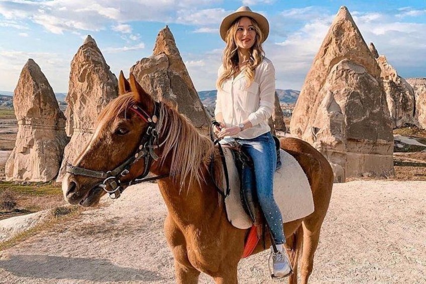 Una persona montando a caballo en un paisaje desértico con formaciones rocosas destacadas. 2