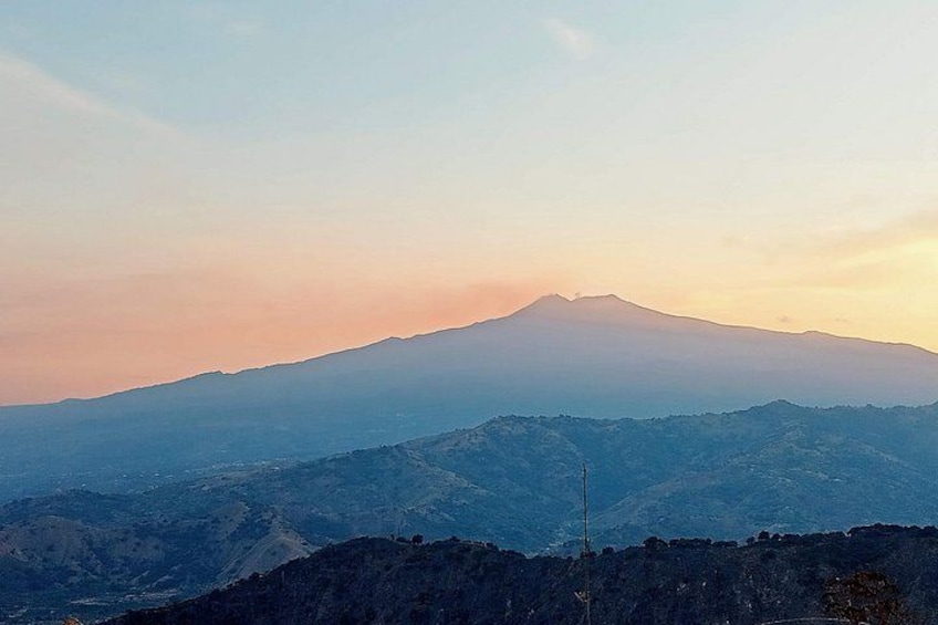 Ein Gebirgszug mit einem markanten Gipfel, möglicherweise ein Vulkan, bei Sonnenaufgang oder Sonnenuntergang. 3