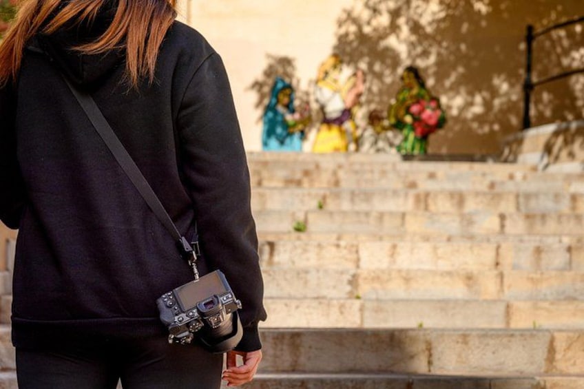 Una persona con una tracolla per macchina fotografica che scende da una scalinata in pietra. 3