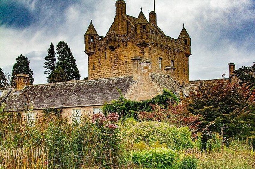 A historic stone castle with turrets, surrounded by overgrown vegetation. 3
