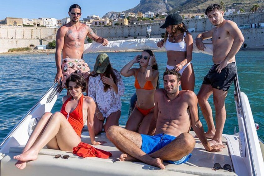 Eine Gruppe von Menschen auf einem Boot in einer Küstenregion, im Hintergrund Gebäude. 5