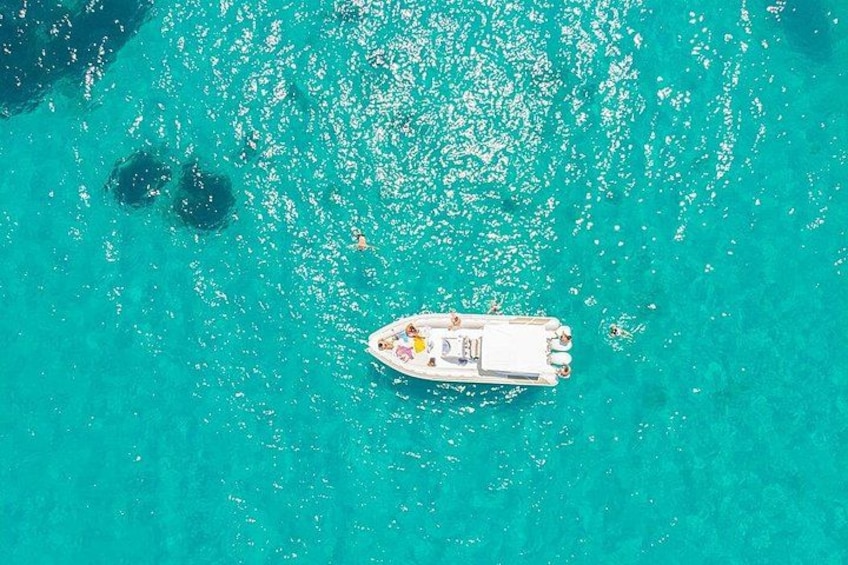A boat on turquoise water with a clear sky. 2