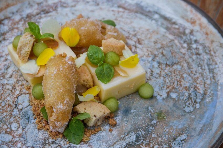 A dessert with green peas, yellow fruit pieces, and a powdered topping on a plate. 4