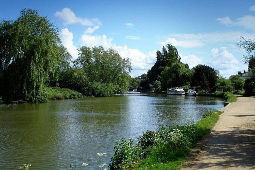 A river with boats, trees, and a path. 2