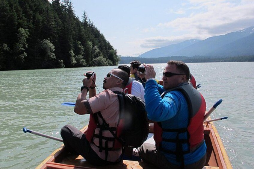 A group of people in a canoe on a lake with mountains in the background. 5