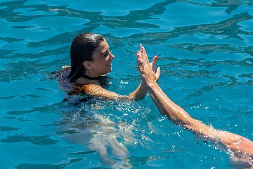 A person swimming in a pool with another person reaching out to them. 2