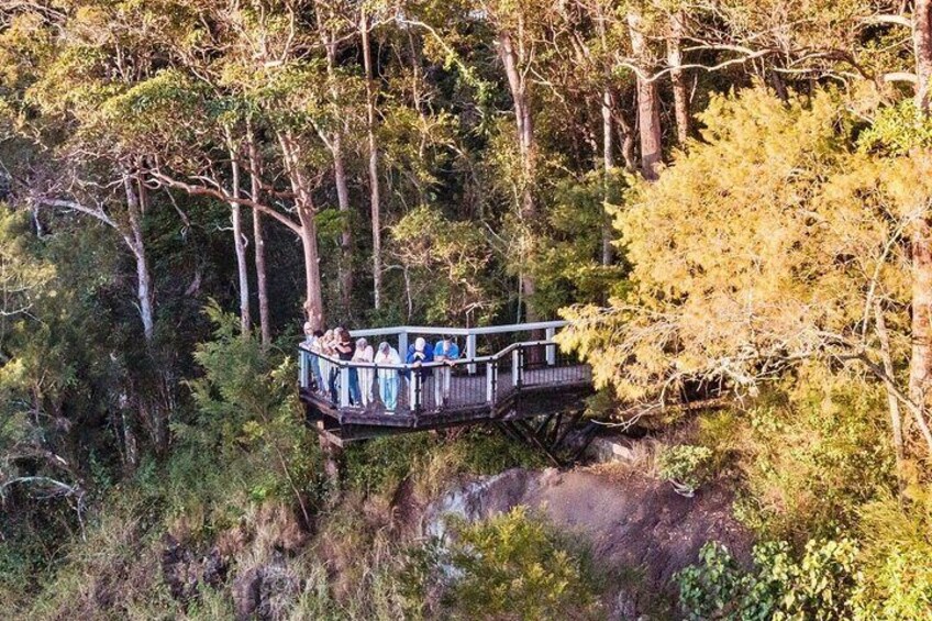 A wooden platform with people in traditional attire, surrounded by dense forest. 3